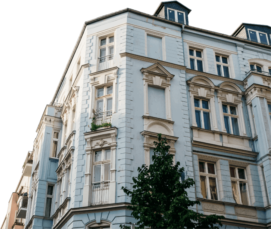 Eckhaus mit blauer Fassade und mehreren Fenstern in einem urbanen Umfeld, sichtbar von der Straßenecke aus.