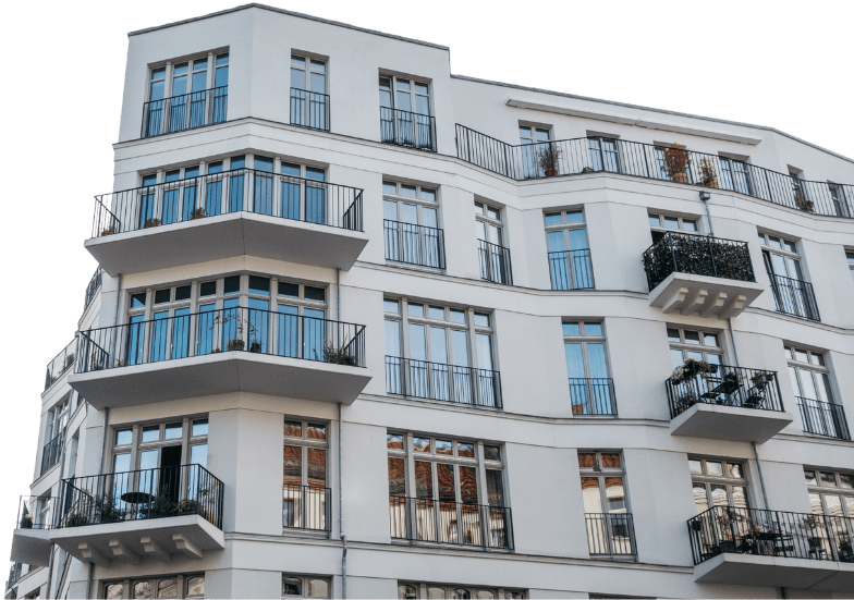 Weißes Wohnhaus mit mehreren Fenstern und Balkonen, das eine moderne Architektur aufweist.